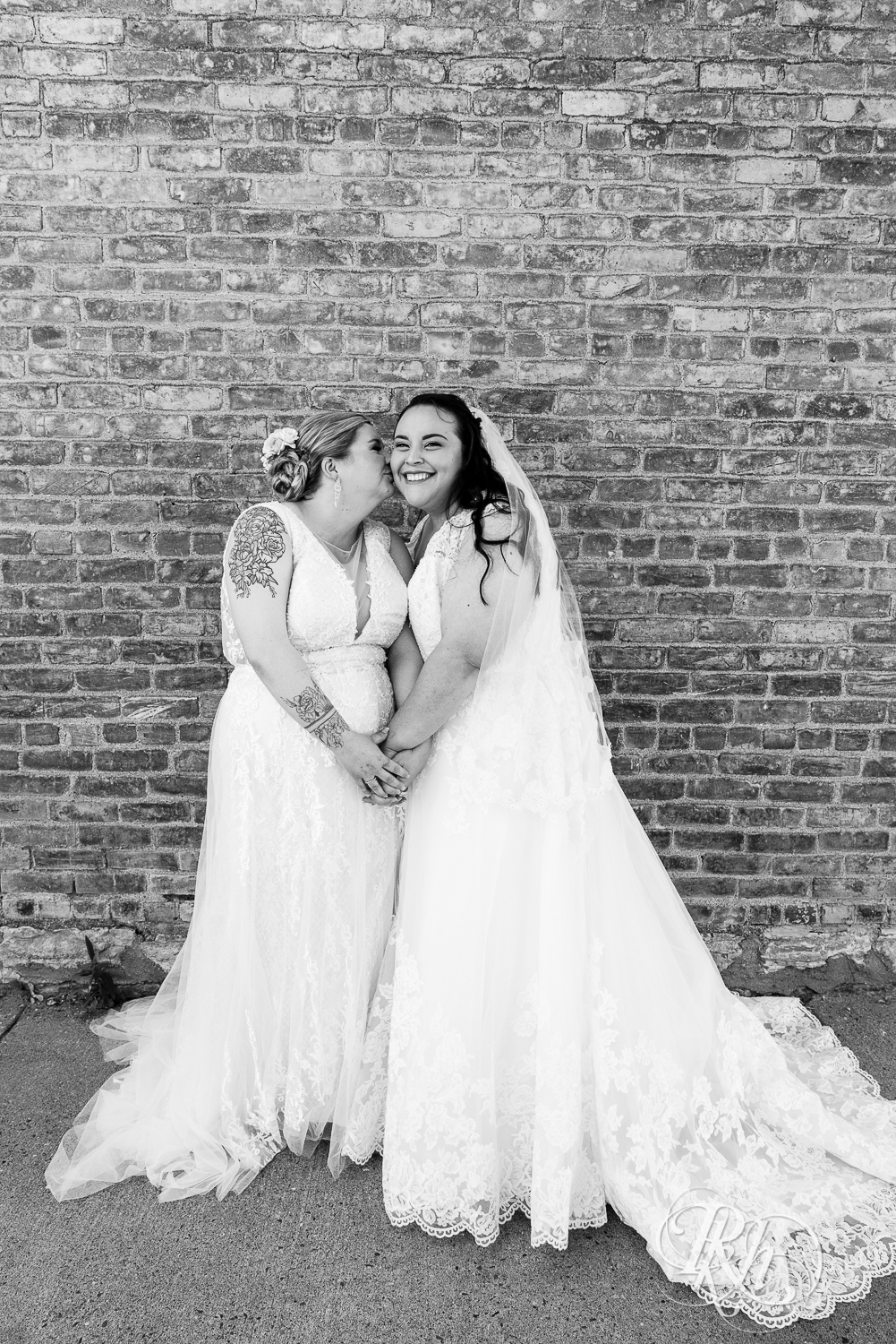 Lesbian brides smile during wedding day at Cannon River Winery in Cannon Falls, Minnesota.