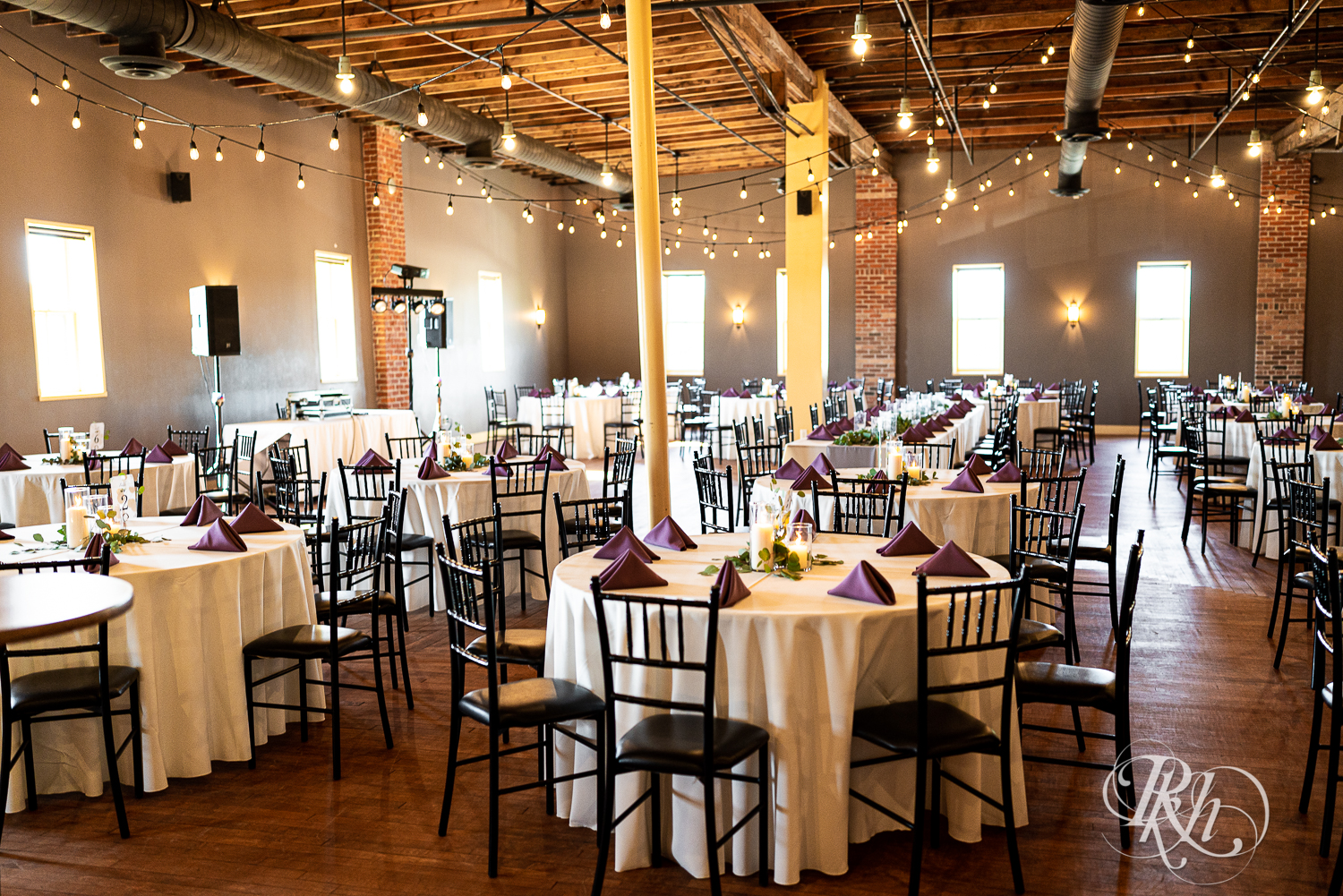 Indoor wedding reception setup with purple accents and string lights at Cannon River Winery in Cannon Falls, Minnesota.