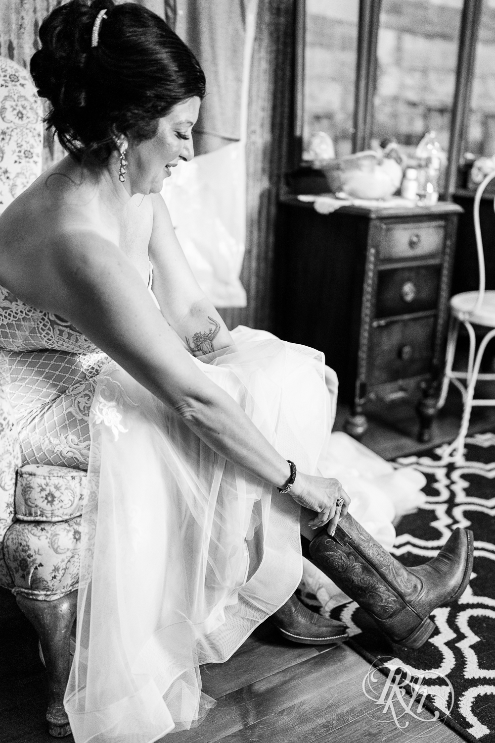 Bride pulling on cowboy boots at Croix View Farm in Osceola, Wisconsin.