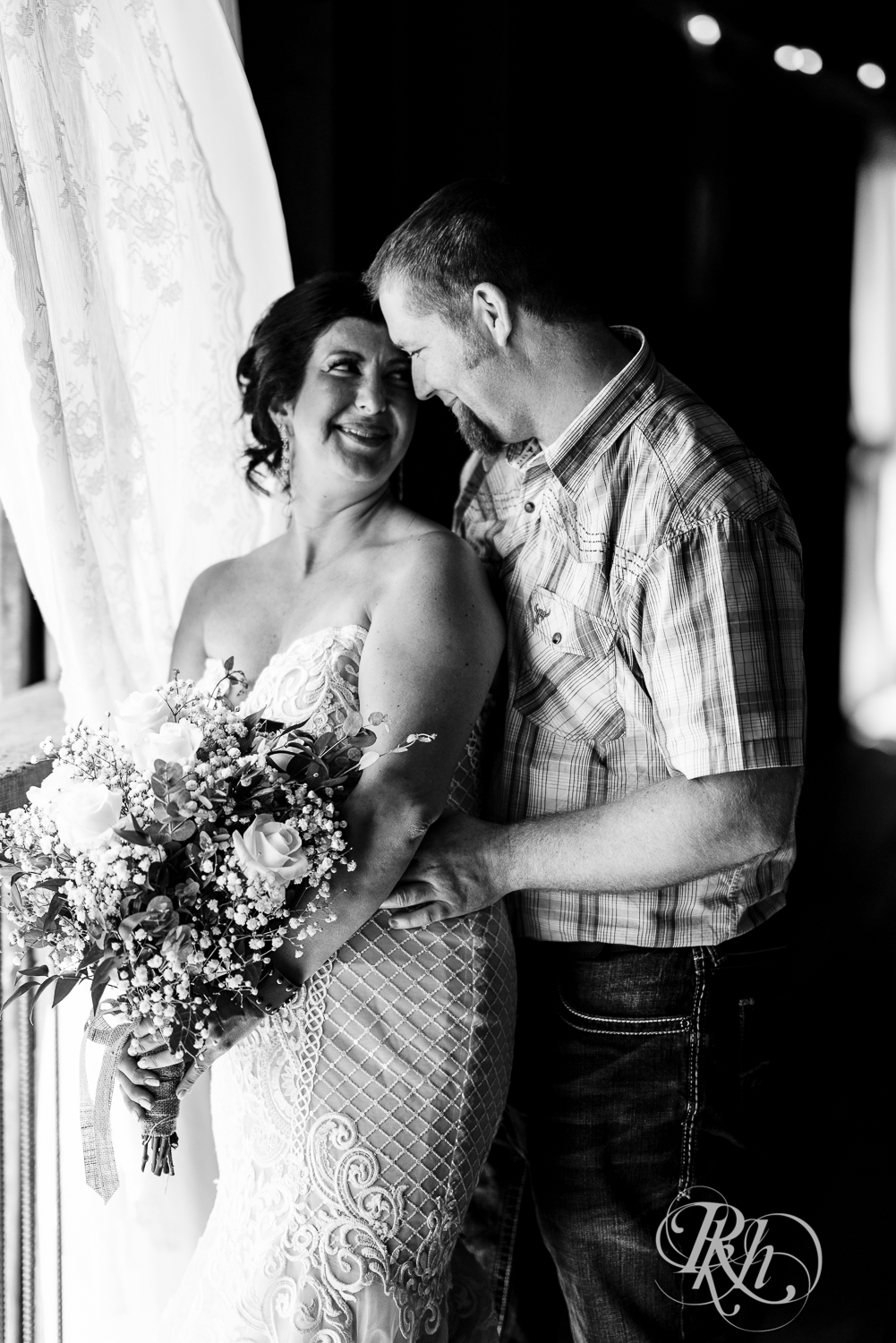 Bride and groom smile by window on wedding day at Croix View Farm in Osceola, Wisconsin.