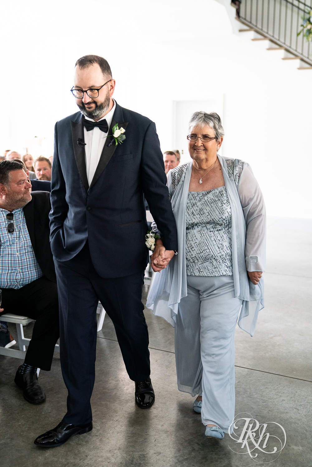 Groom walking mom down the aisle during wedding ceremony at The Hutton House in Medicine Lake, Minnesota.