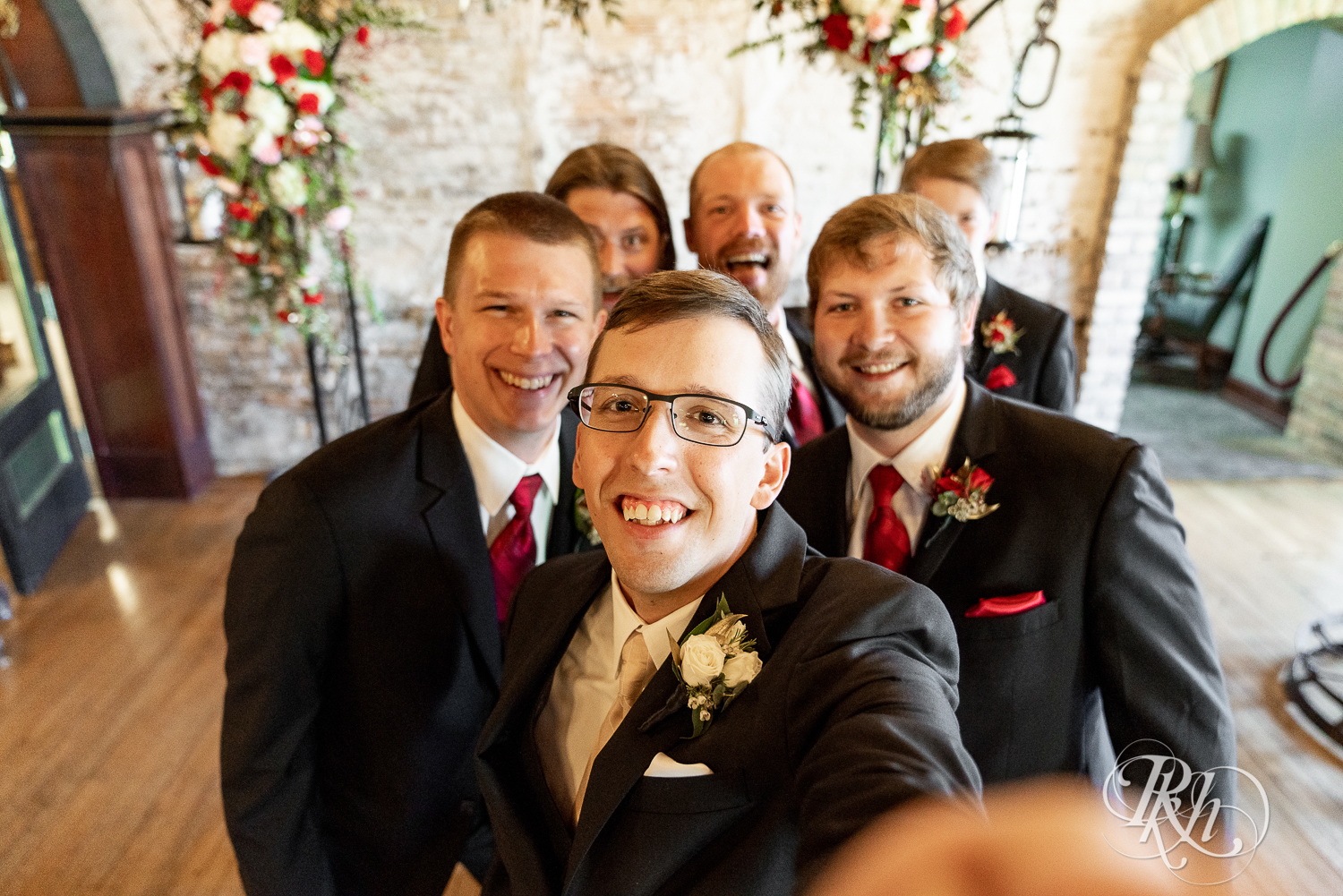 Wedding party in black suits smiling at Kellerman's Event Center in White Bear Lake, Minnesota.