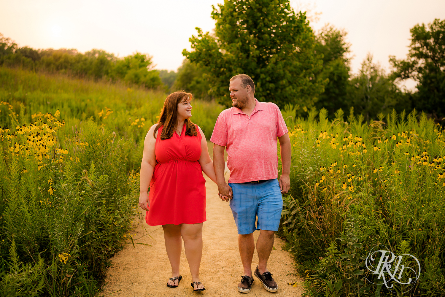 Man and women in orange dress walk in flowers at sunset at Lebanon Hills Regional Park in Eagan, Minnesota.