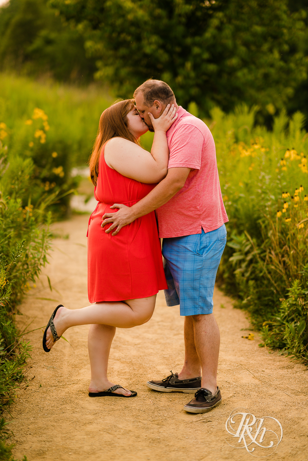 Man and women in orange dress kiss at sunset at Lebanon Hills Regional Park in Eagan, Minnesota.