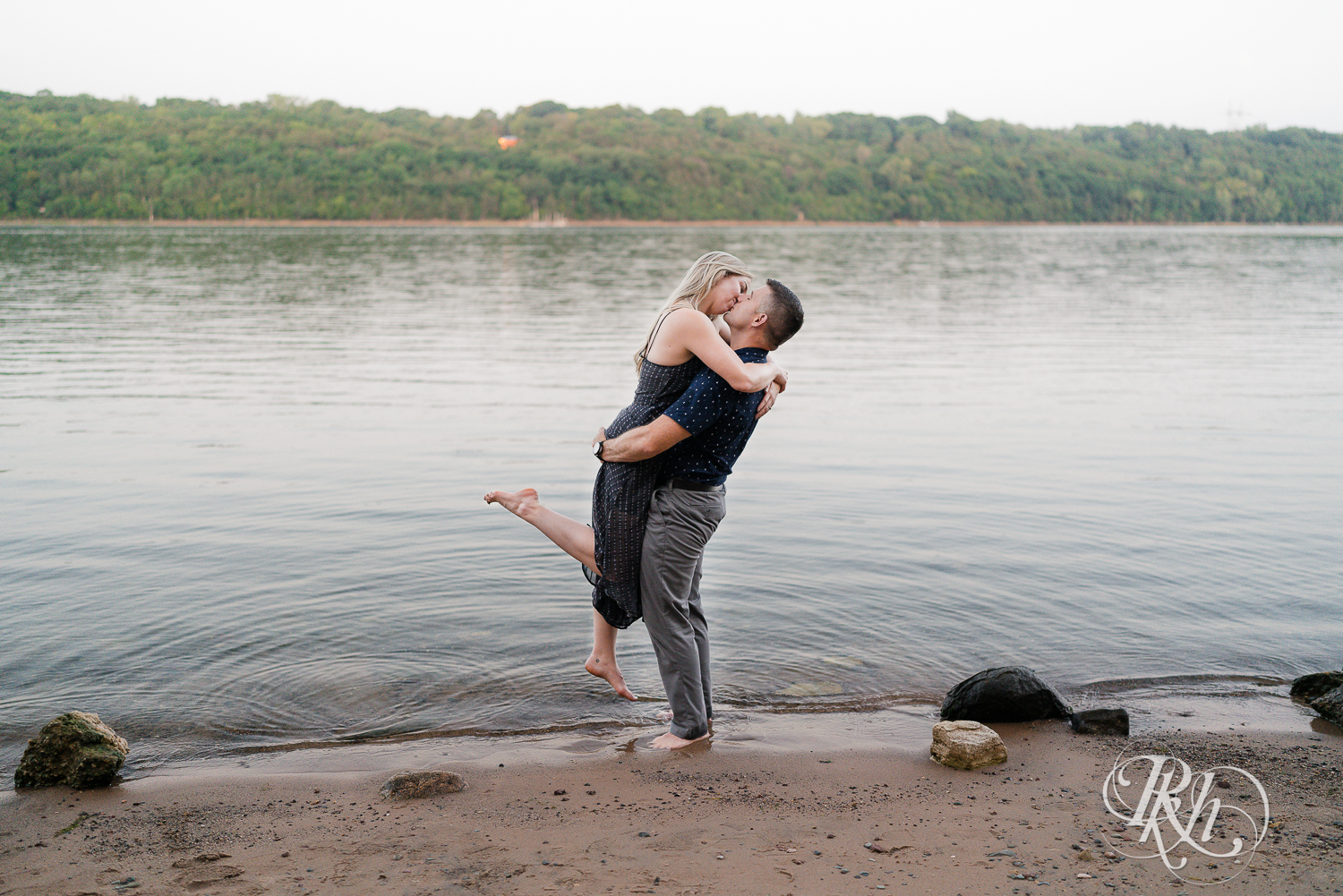 Man and woman in blue dress kiss on beach at Afton State Park in Hastings, Minnesota.