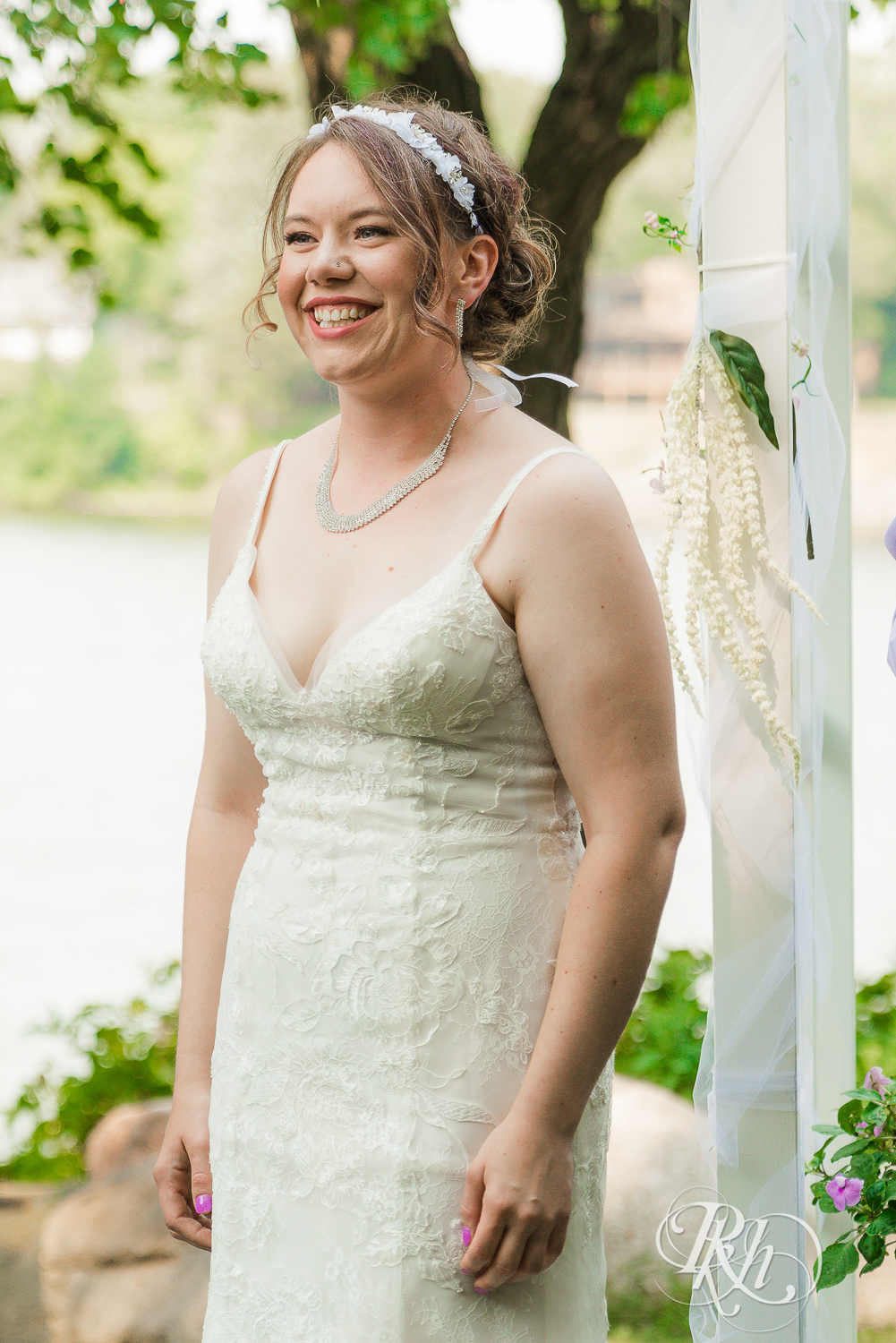 Lesbian bride smiling at her bride during outdoor wedding ceremony in Minnesota.