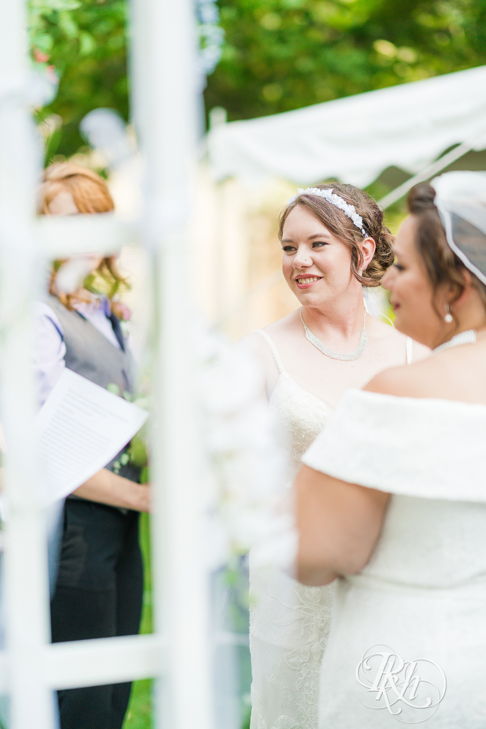 Lesbian brides smiling during outdoor wedding ceremony in Minnesota.
