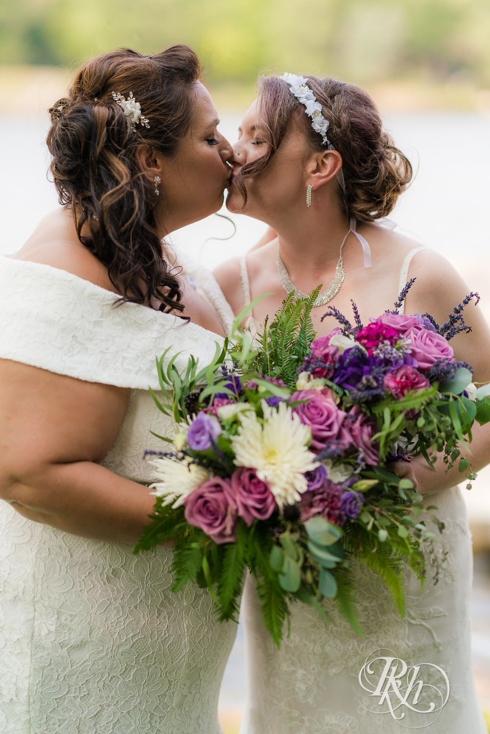 Lesbian brides kissing by the water at wedding in Champlin, Minnesota.