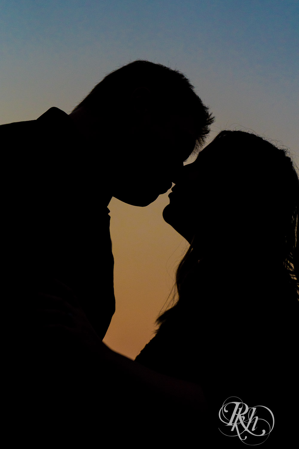 Man and woman kissing in silhouette during sunset at Lebanon Hills Regional Park in Eagan, Minnesota.