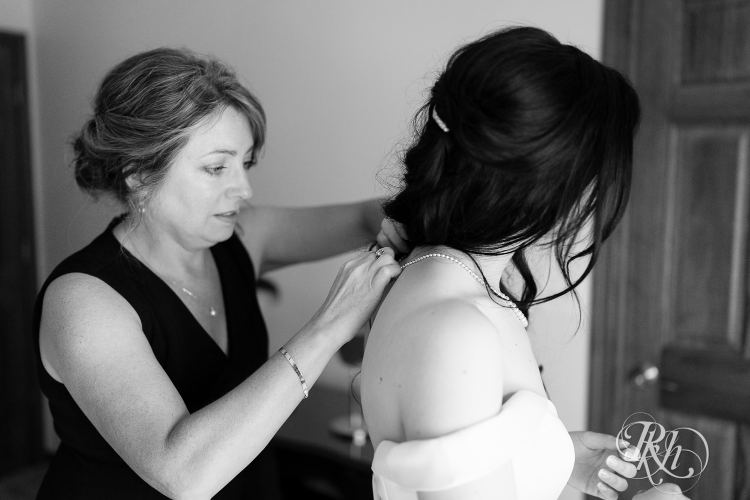 Mom put's necklace on a bride on her wedding day.