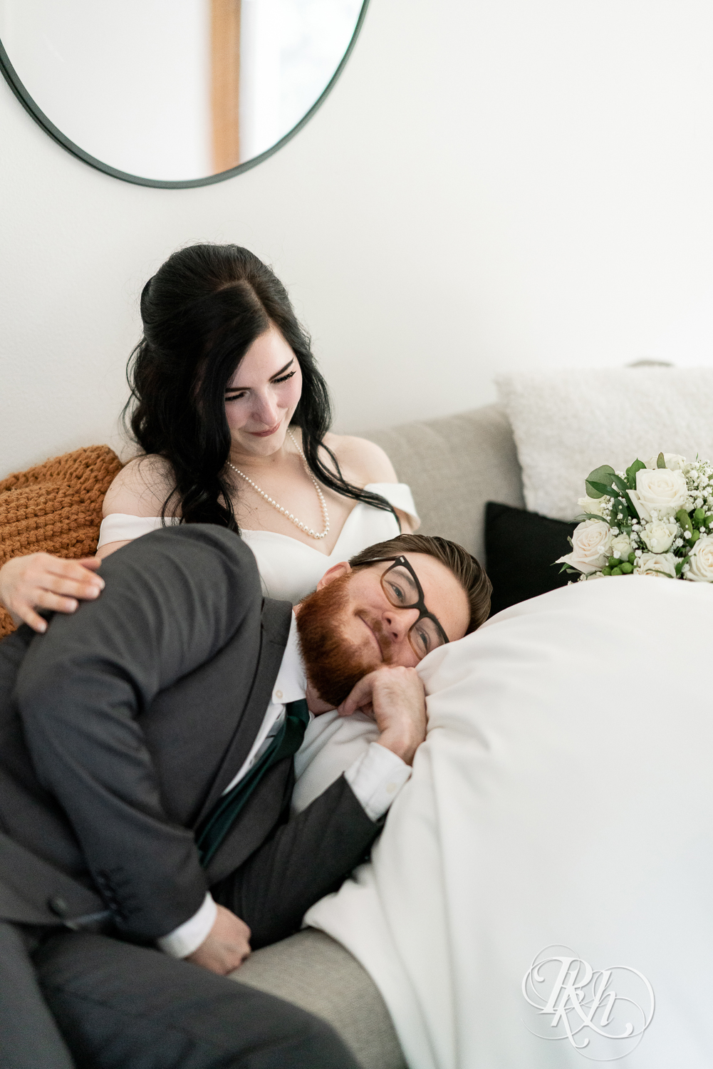 Groom lays on bride's lap on couch at their house wedding in Sartell, Minnesota.