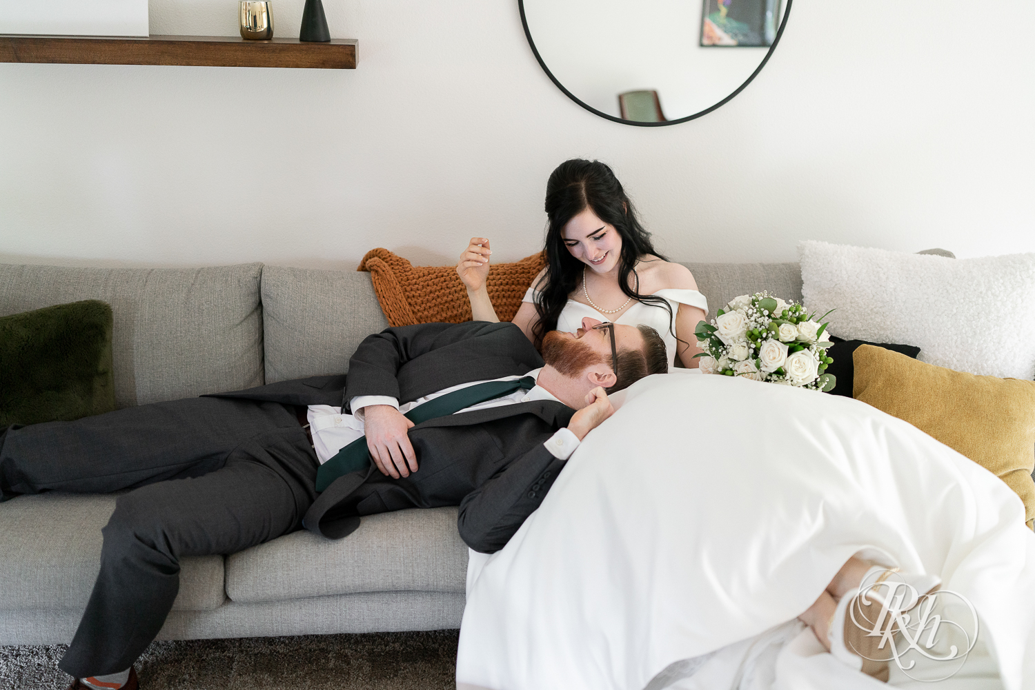 Bride and groom laugh on couch at their house wedding in Sartell, Minnesota.