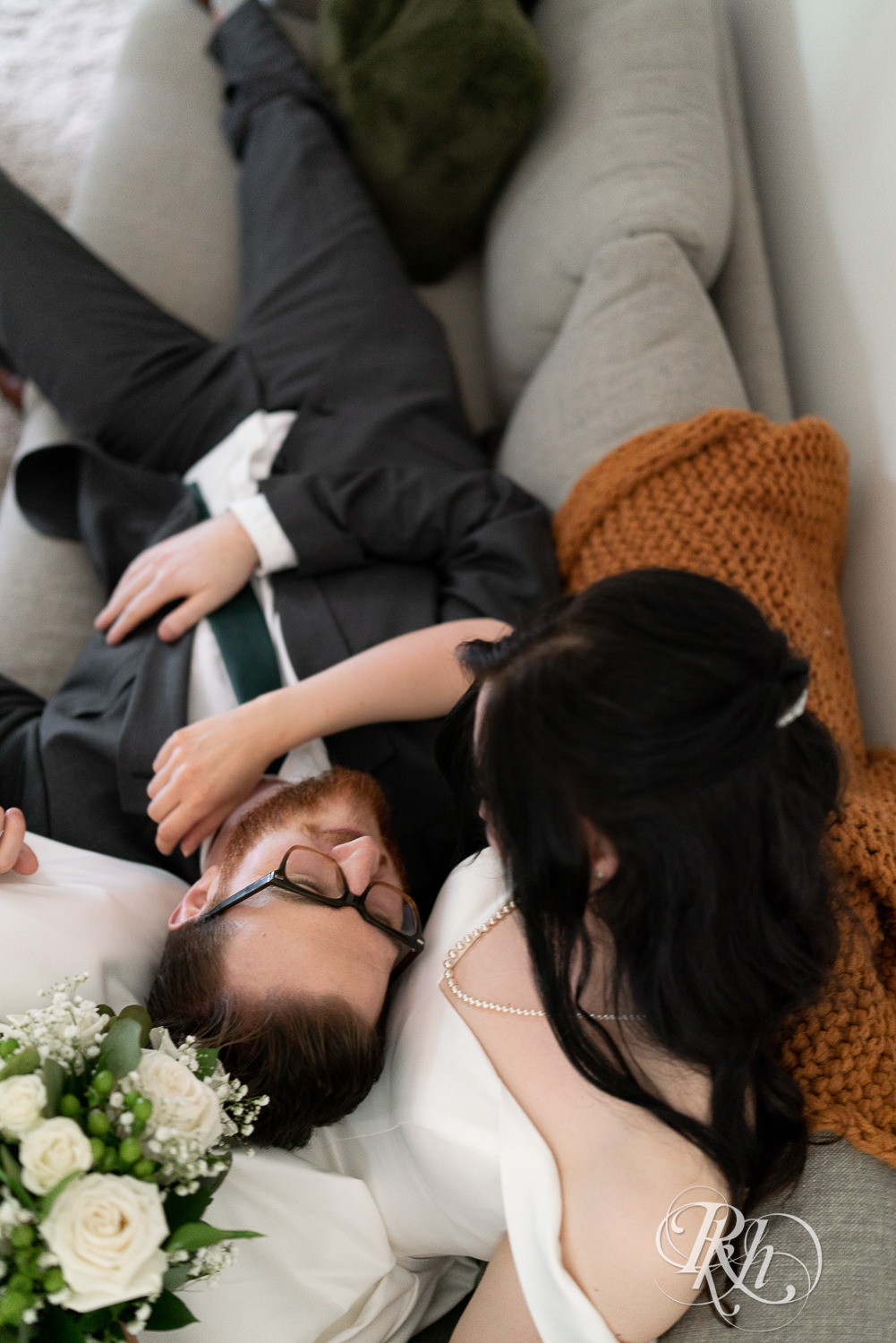 Bride and groom smiles on couch at their house wedding in Sartell, Minnesota.