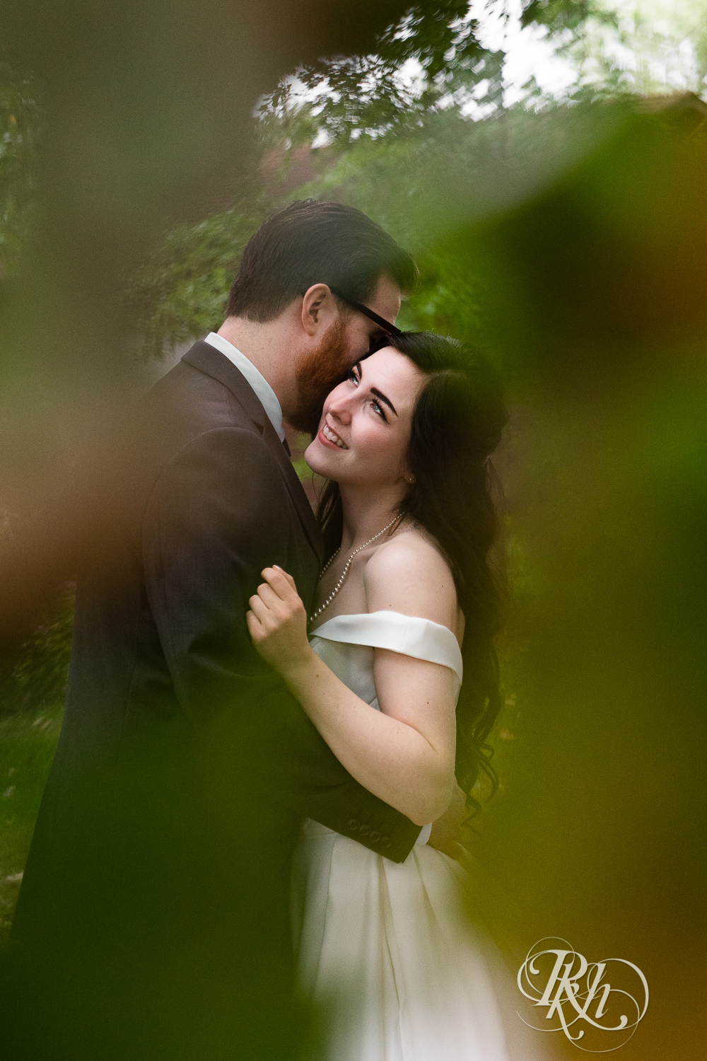 Bride and groom kiss in trees at their house wedding in Sartell, Minnesota.