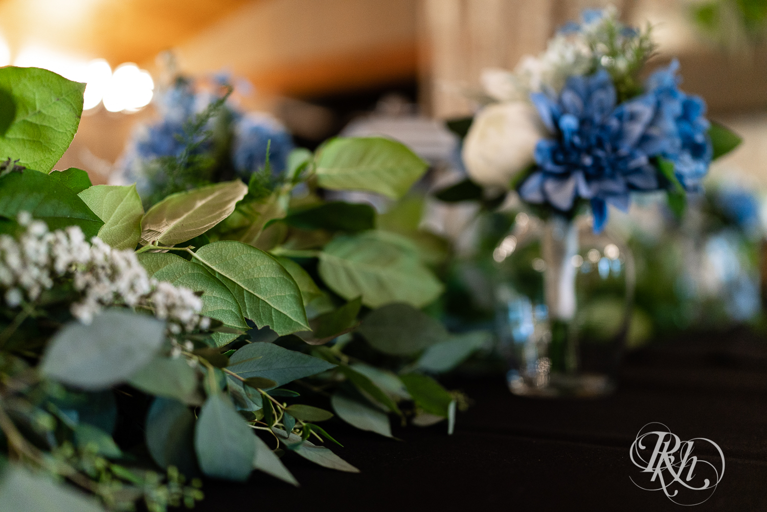 Indoor wedding reception setup at 7 Vines Vineyard in Dellwood, Minnesota with eucalyptus and blue flowers.