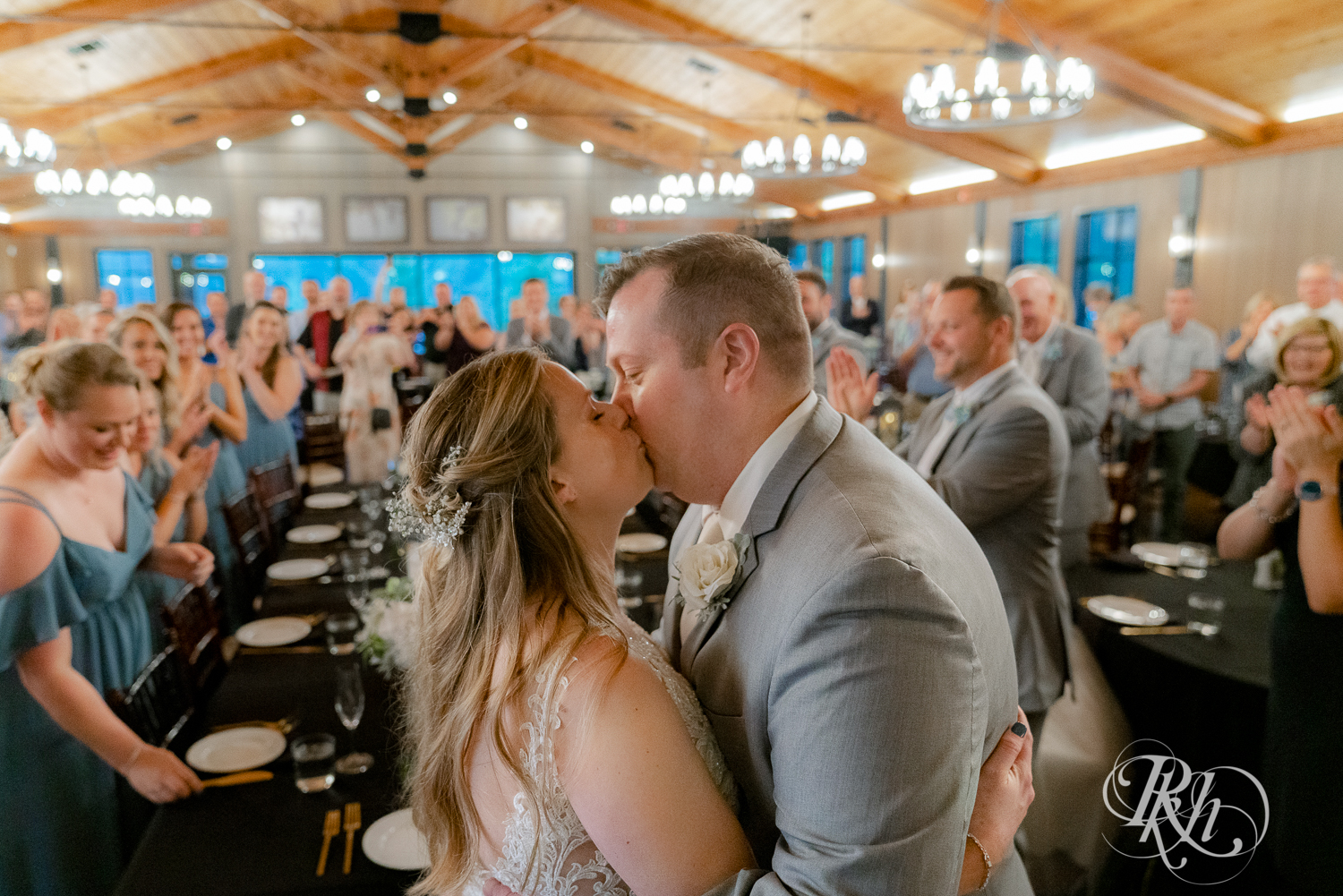 Bride and groom kiss at head table during wedding reception at 7 Vines Vineyard in Dellwood, Minnesota.