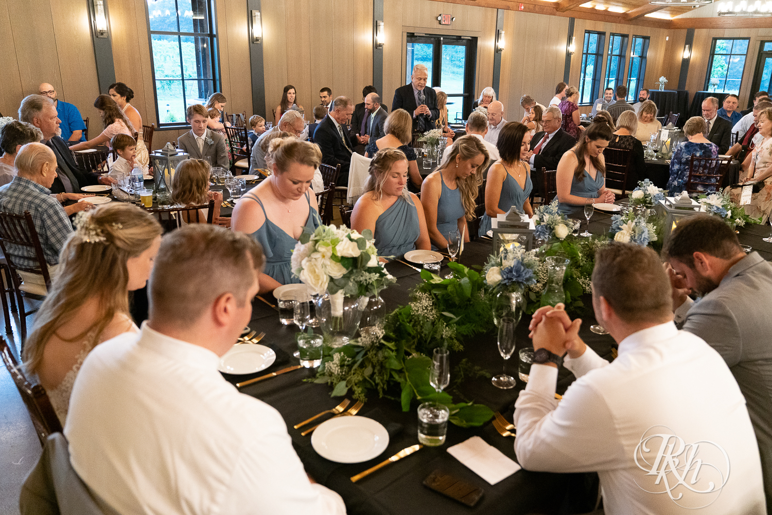 Bride and groom pray at head table during wedding reception at 7 Vines Vineyard in Dellwood, Minnesota.