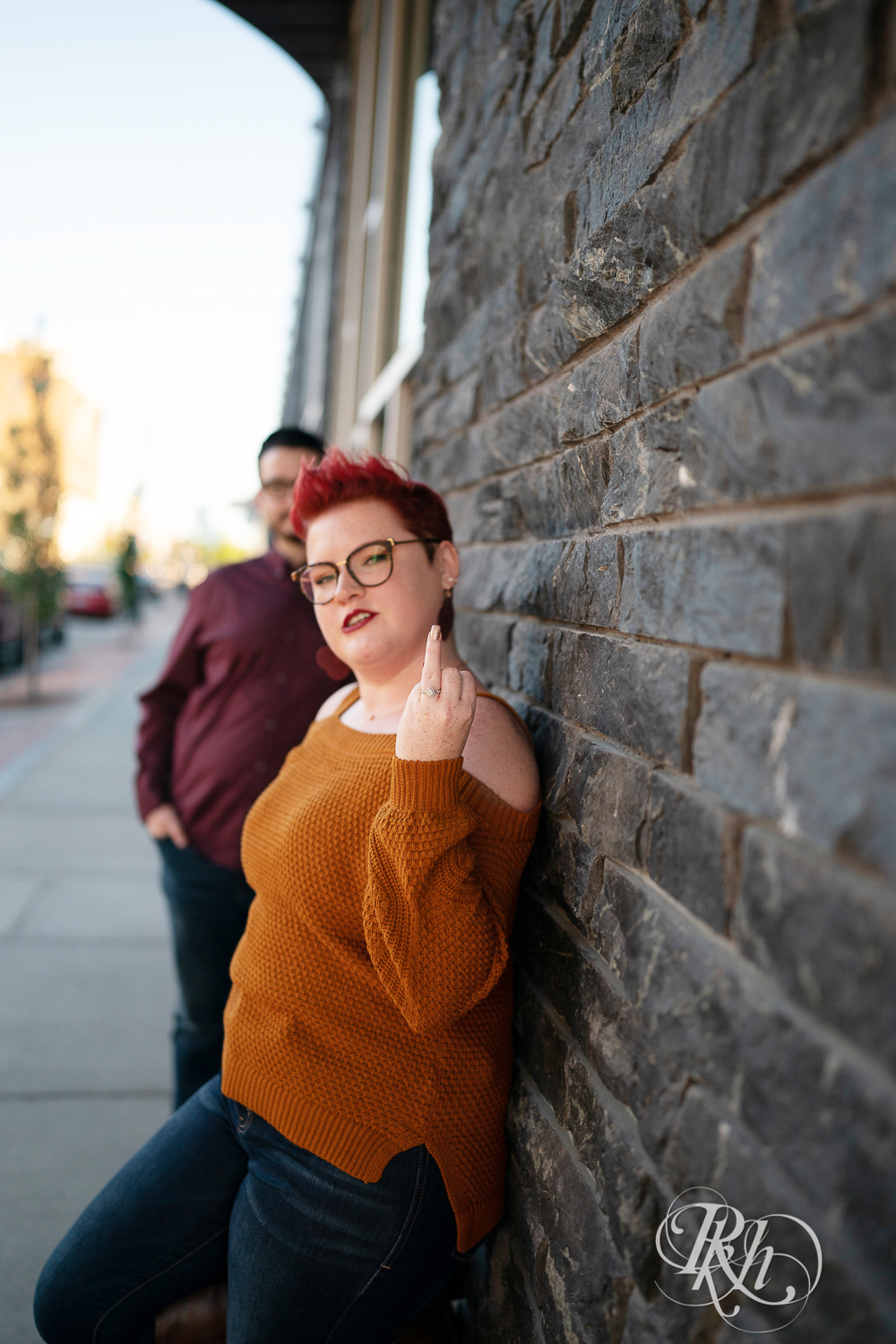 Man and woman with glasses and pixie red hair showing off engagement ring in Phoenix Park in Eau Claire, Wisconsin.