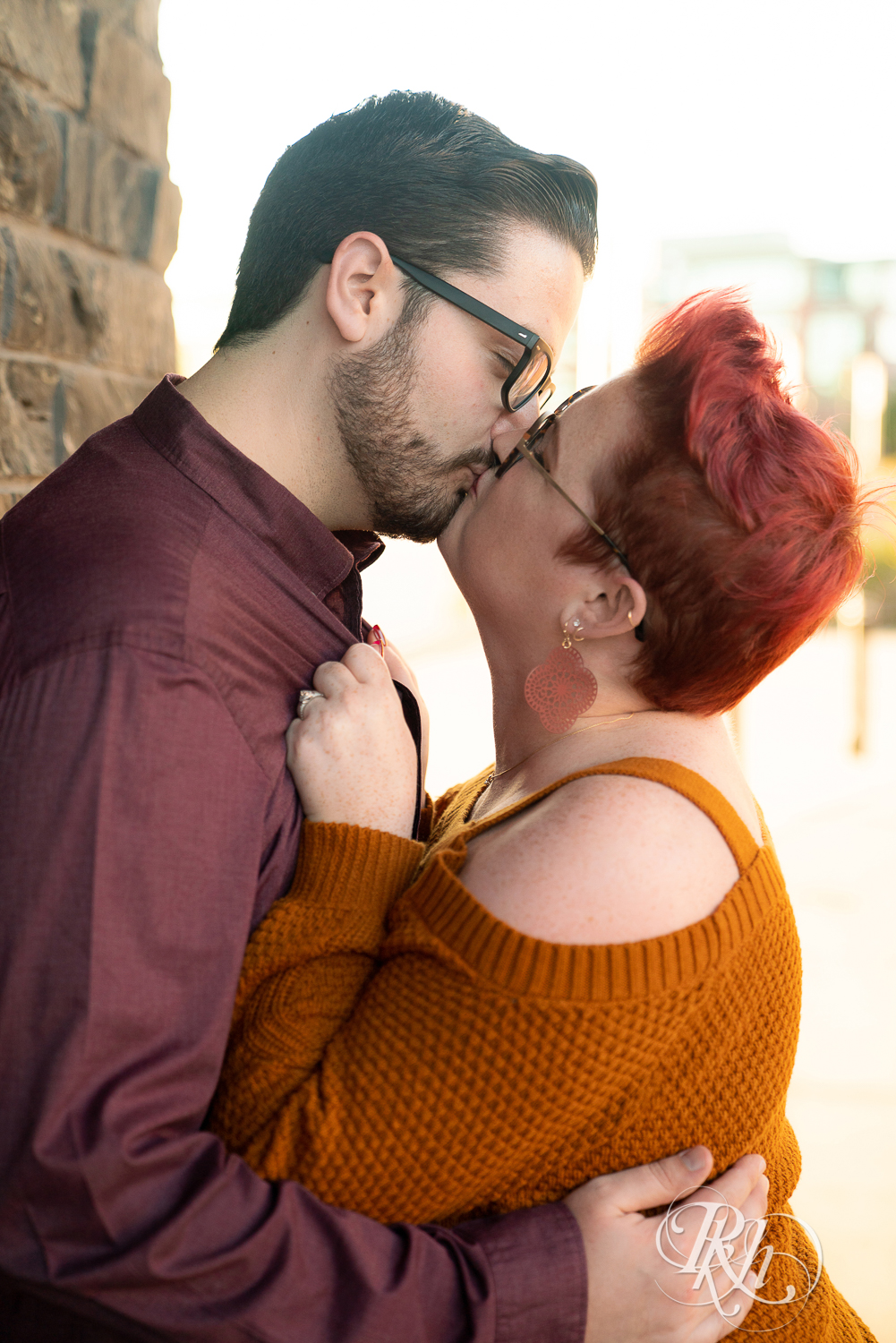 Man and woman with glasses and pixie red hair kissing in Phoenix Park in Eau Claire, Wisconsin.
