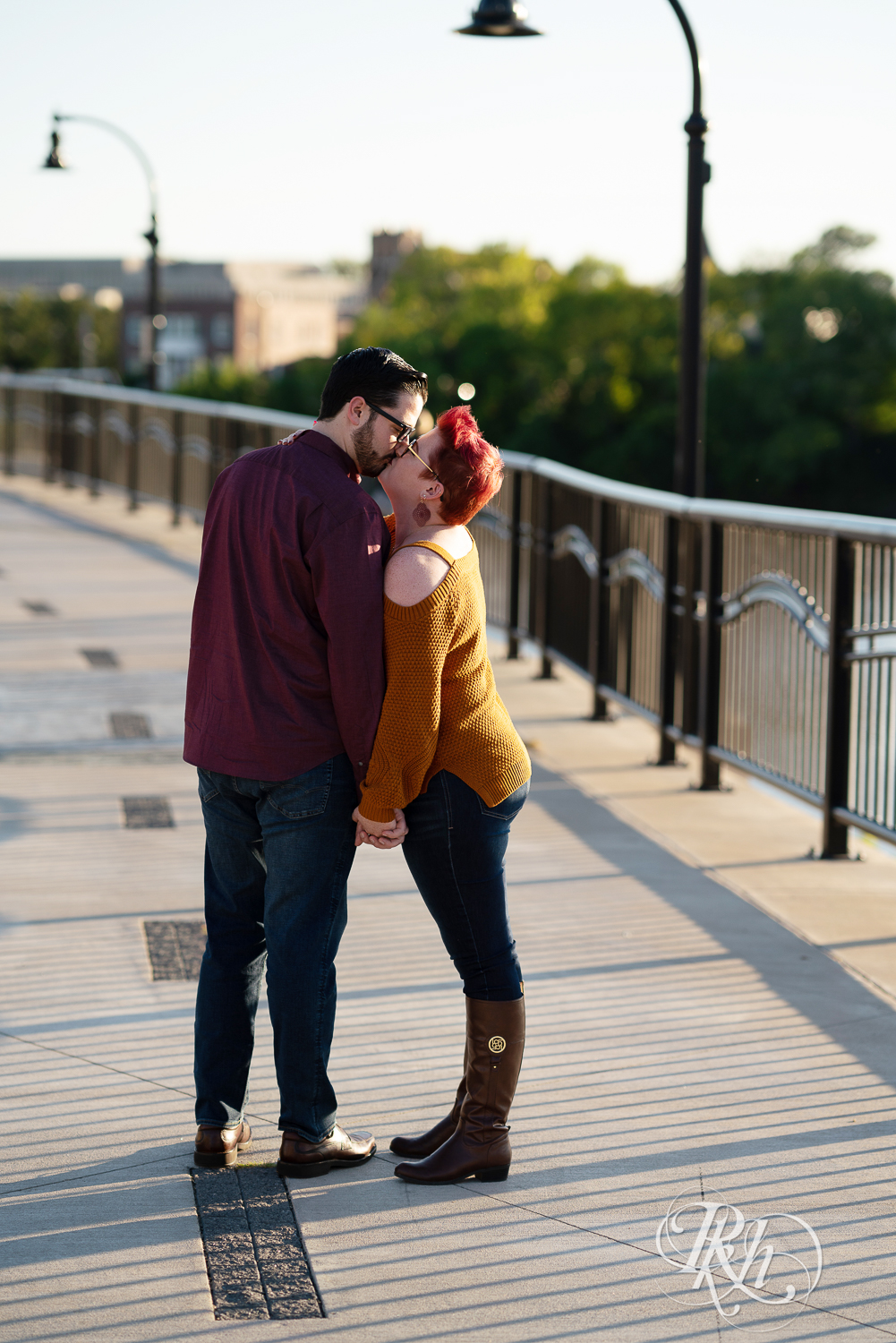 Man and woman with glasses and pixie red hair kissing in Phoenix Park in Eau Claire, Wisconsin.