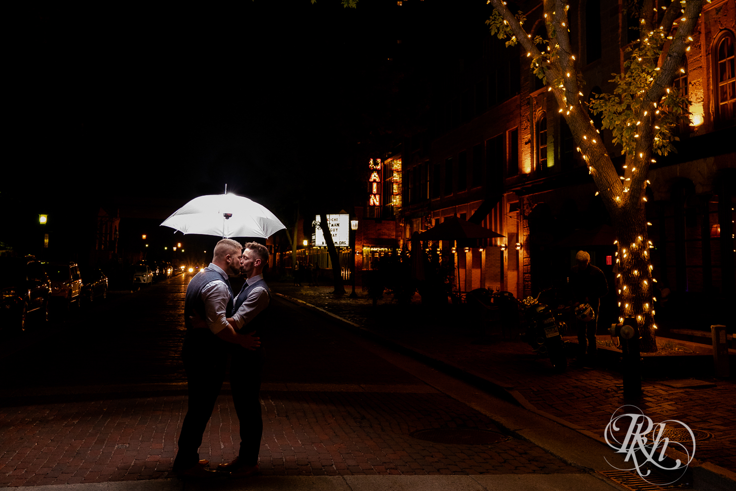 Grooms kissing under an umbrella in the middle of the street in Minneapolis, Minnesota.