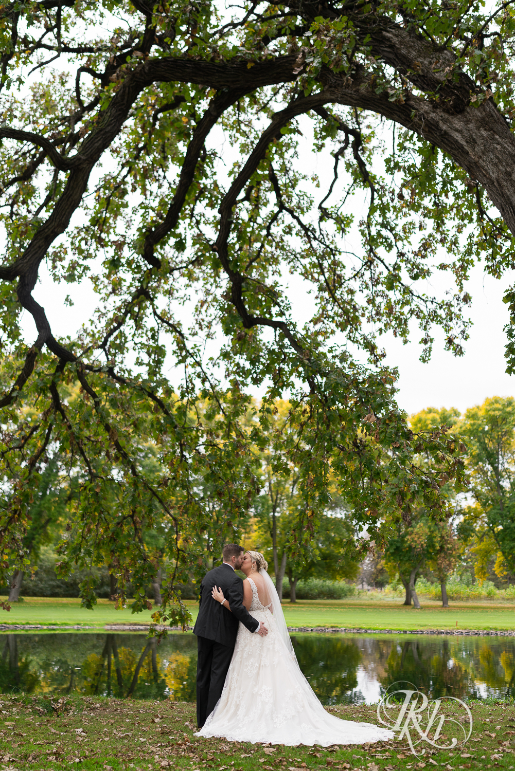 Bride and groom kiss under tree at Hastings Golf Club in Hastings, Minnesota.