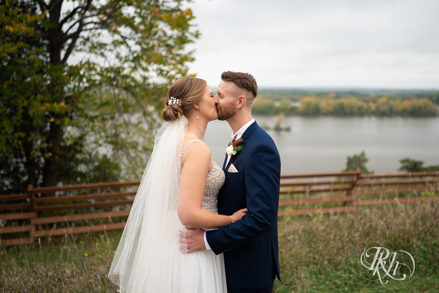 Bride and groom kissing in front of the river at Schaar's Bluff in Hastings, Minnesota. 