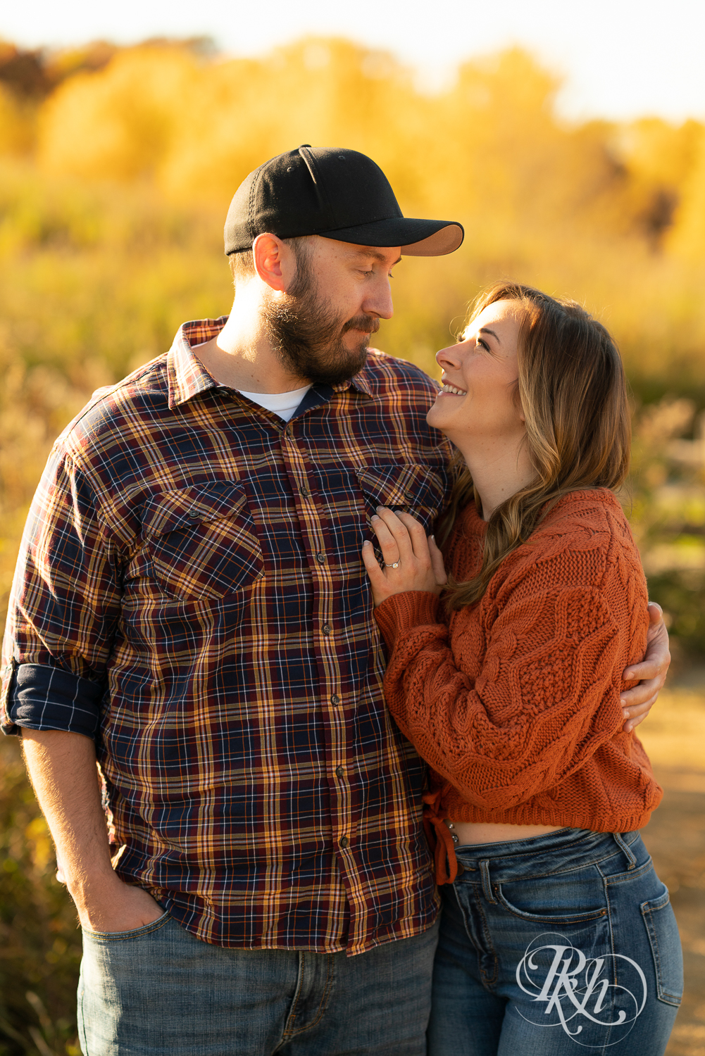 Man in flannel and woman in jeans and sweater snuggling in sunset in Eagan, Minnesota.