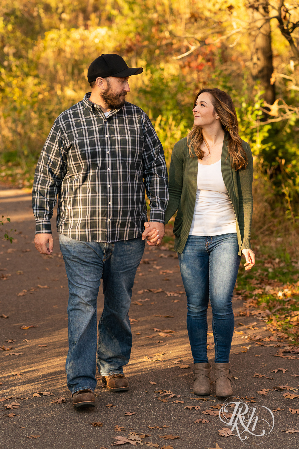 Man in flannel and woman in jeans and sweater walking down a path during sunset in Eagan, Minnesota.
