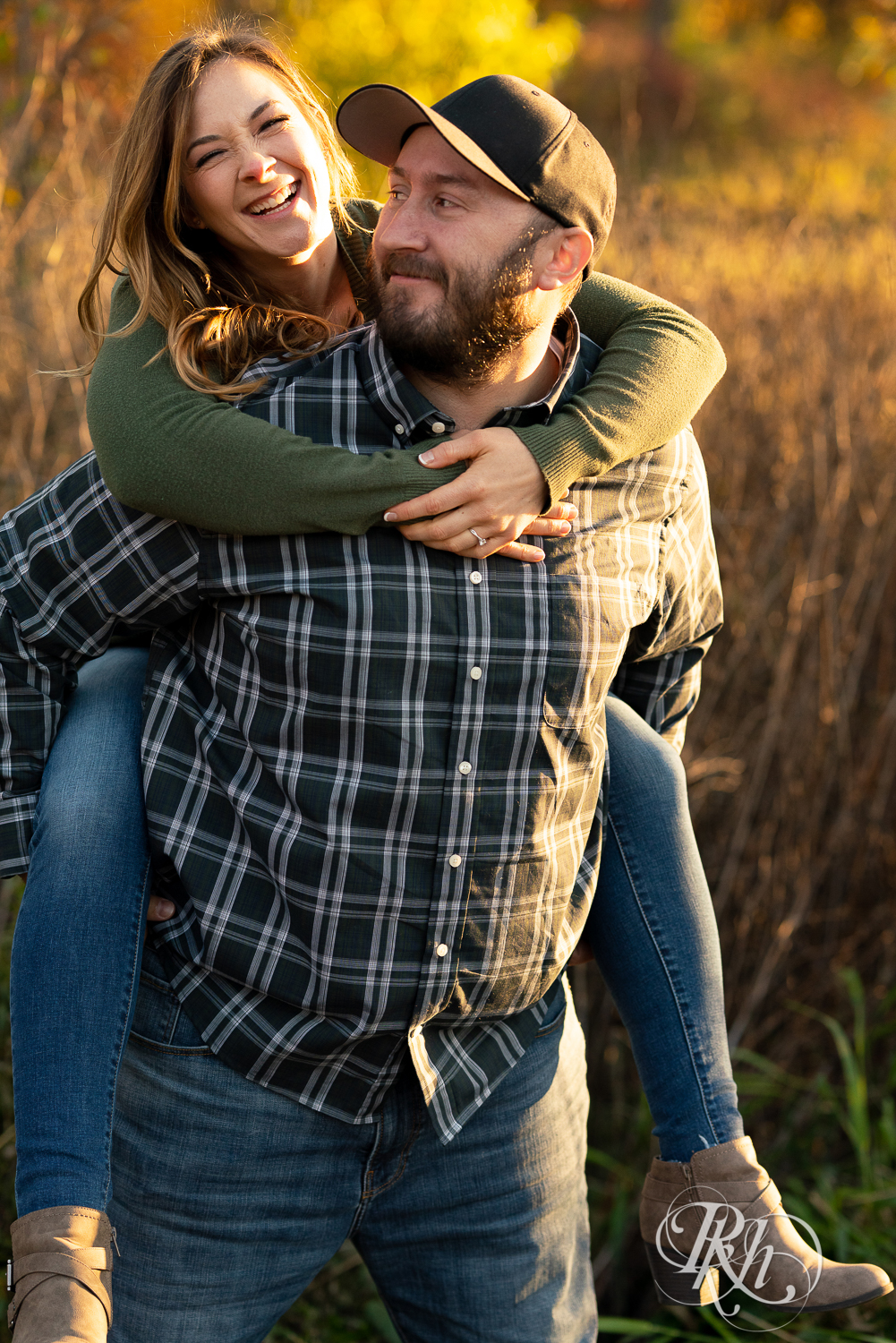 Man in flannel giving woman in jeans and sweater a piggyback ride during sunset in Eagan, Minnesota.