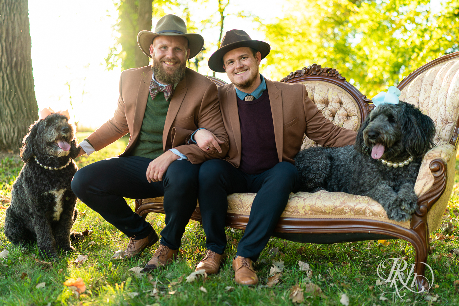 Two gay men smiling in suits and hats with Sheepadoodles in Belle Plaine, Minnesota.