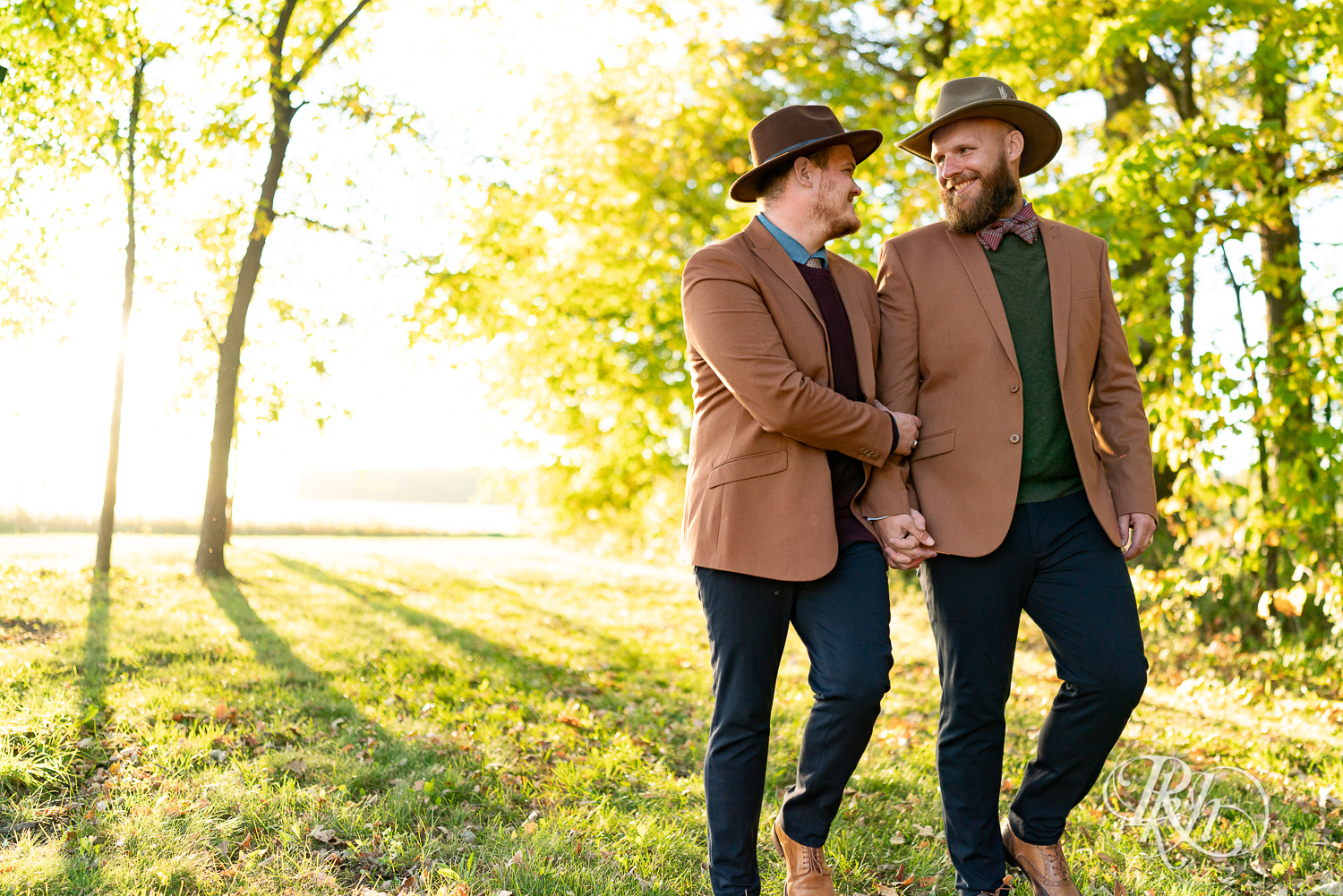 Two gay men walking in suits and hats at sunset in Belle Plaine, Minnesota.