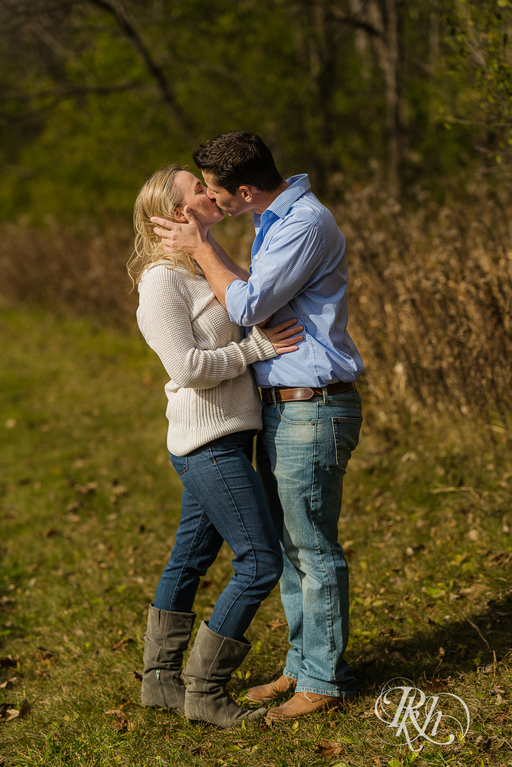 Man kisses blonde woman in grass during fall engagement photography session in Chaska, Minnesota.