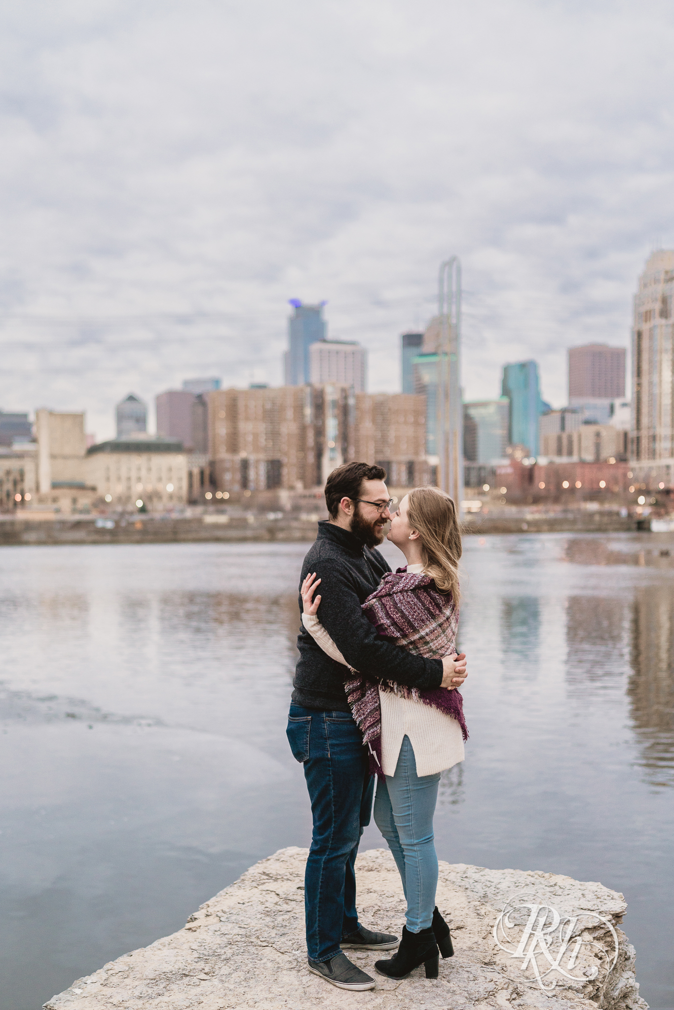 Man and woman hugging in front of Mississippi River in Minneapolis, Minnesota at sunrise. 