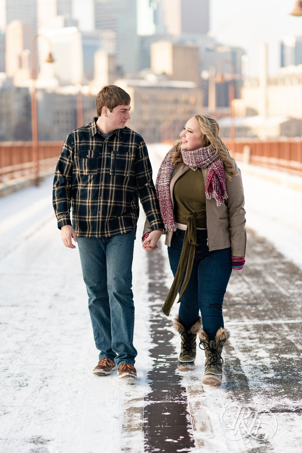 Man and woman walking and holding hands on the Stone Arch Bridge in Minneapolis, Minnesota.