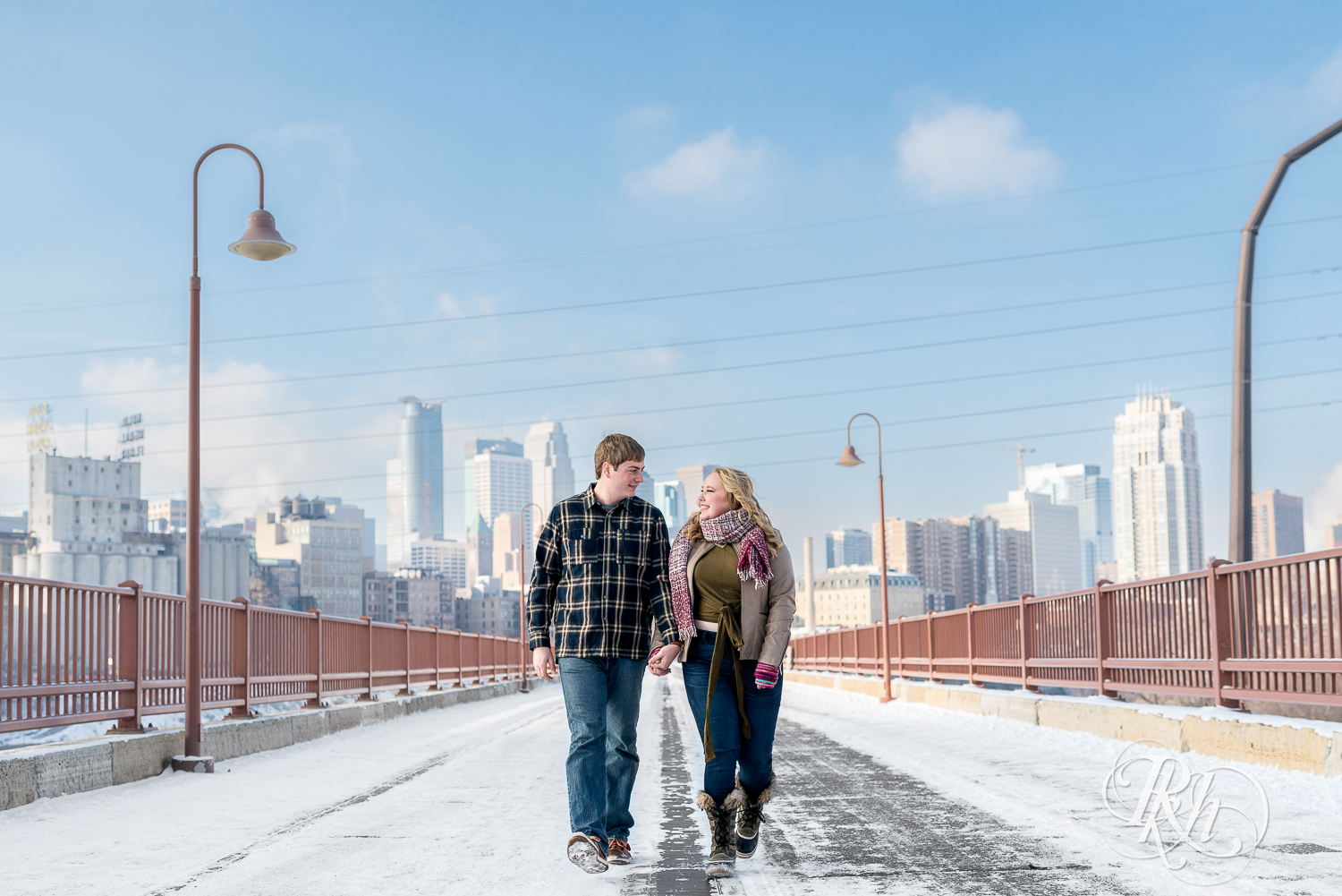 Man and woman walking and holding hands on the Stone Arch Bridge in Minneapolis, Minnesota.