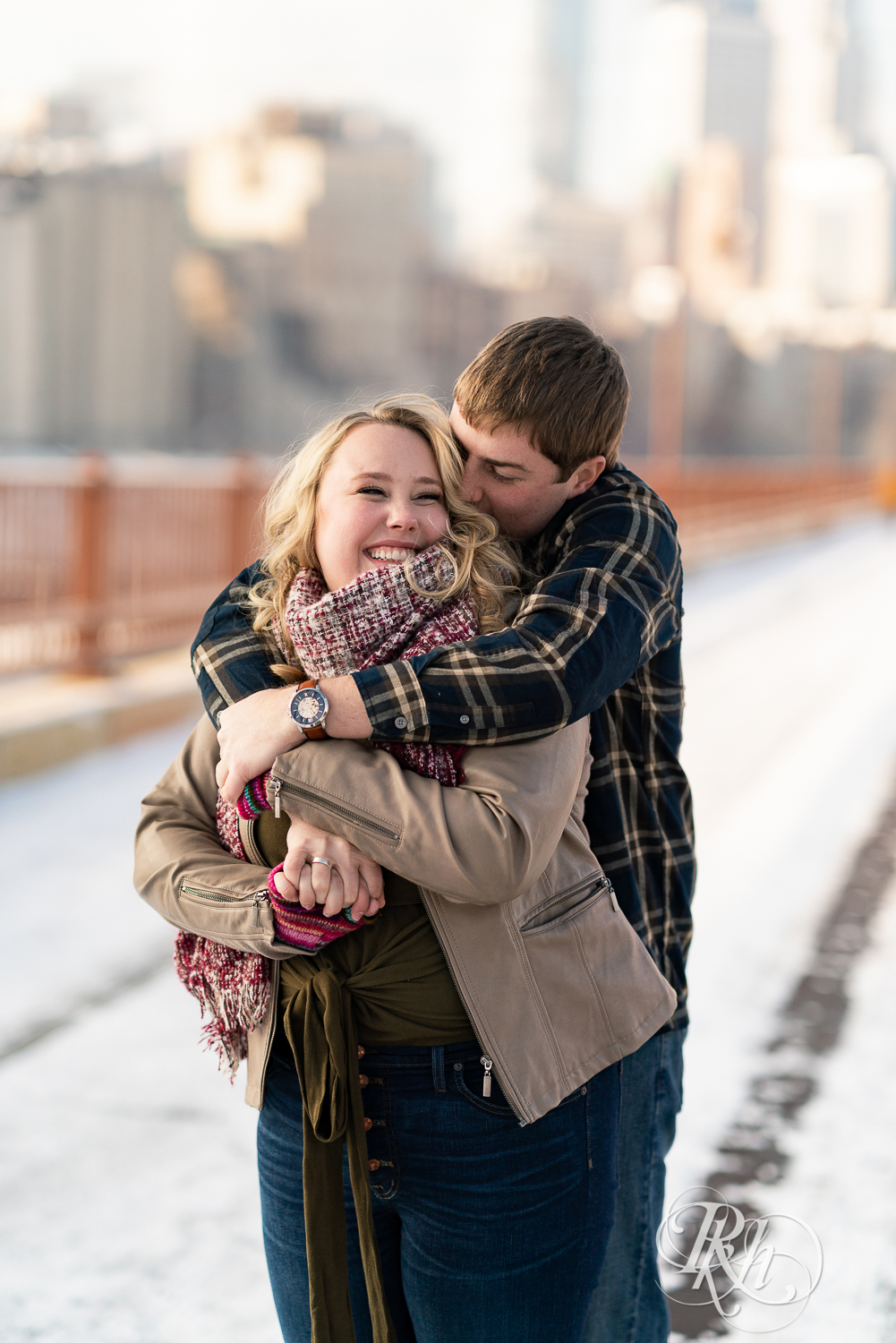 Man and woman kissing in the snow on the Stone Arch Bridge in Minneapolis, Minnesota.