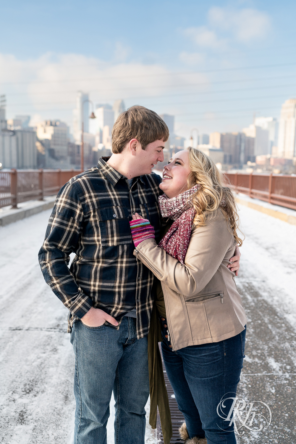 Man and woman smiling in the snow on the Stone Arch Bridge in Minneapolis, Minnesota.