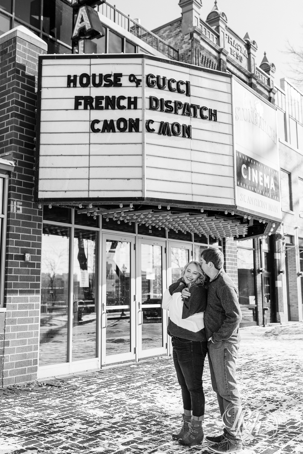 Man and woman snuggling in the snow in front of movie theater in Saint Anthony Main in Minneapolis, Minnesota.