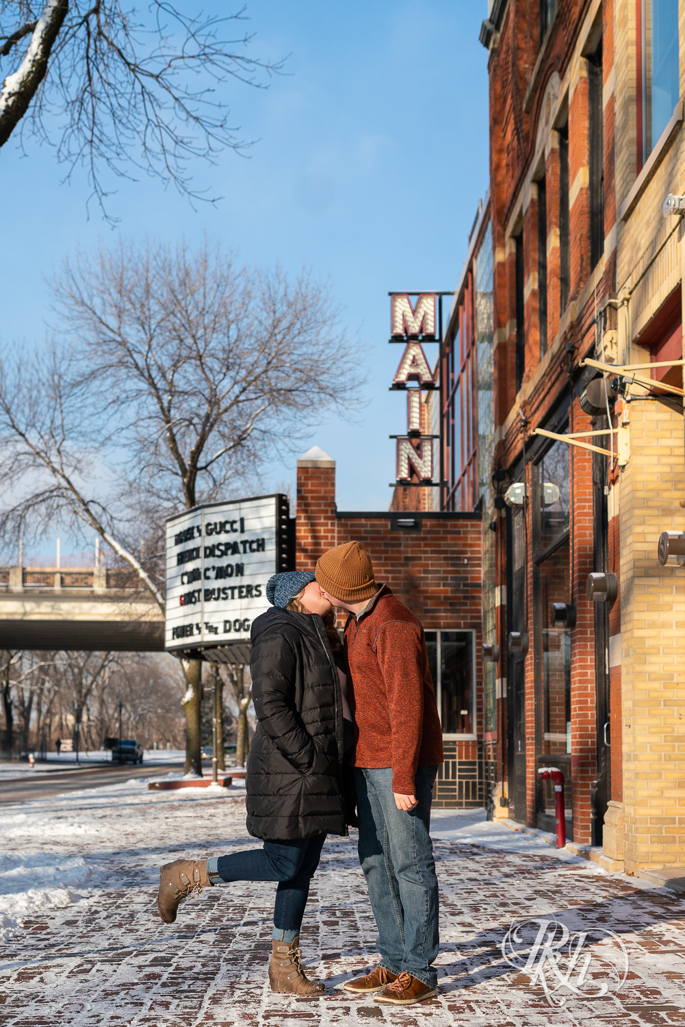 Man and woman kissing in the snow in front of movie theater in Saint Anthony Main in Minneapolis, Minnesota.