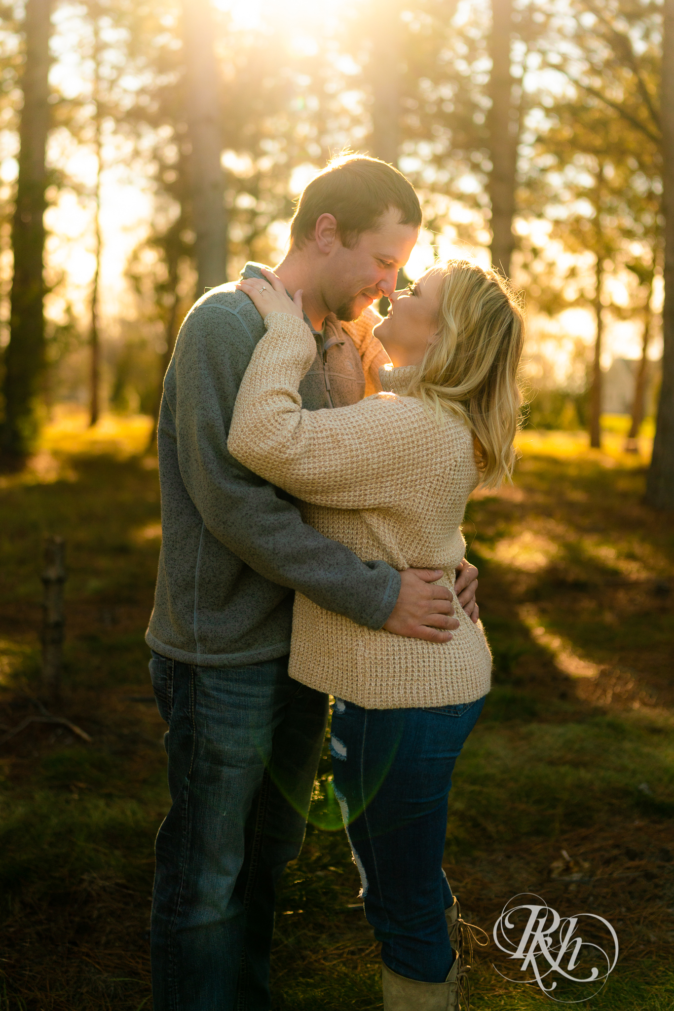 Man and woman kissing in sunlight in between trees at Hansen Tree Farm in Anoka, Minnesota.
