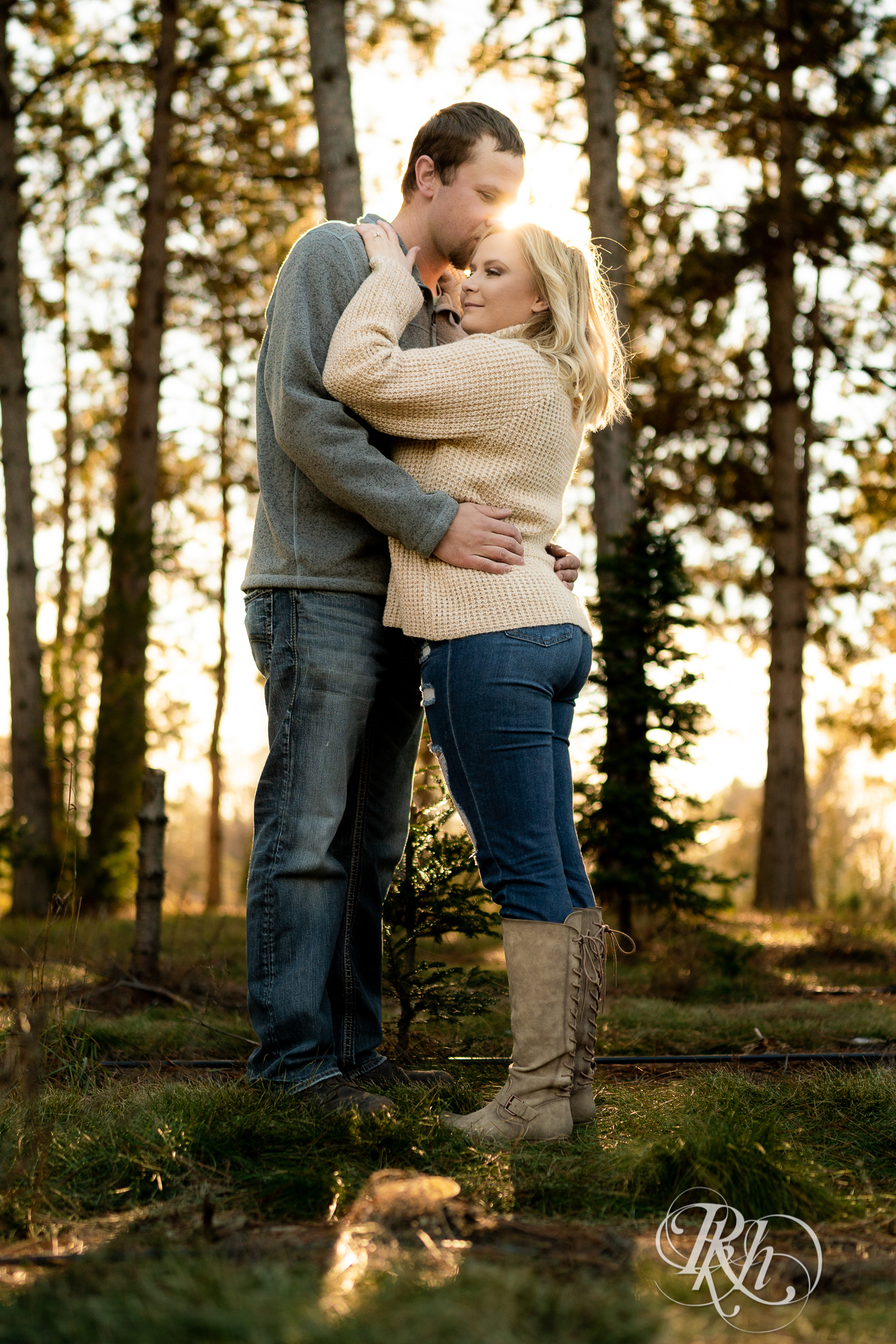 Man and woman kissing in sunlight in between trees at Hansen Tree Farm in Anoka, Minnesota.