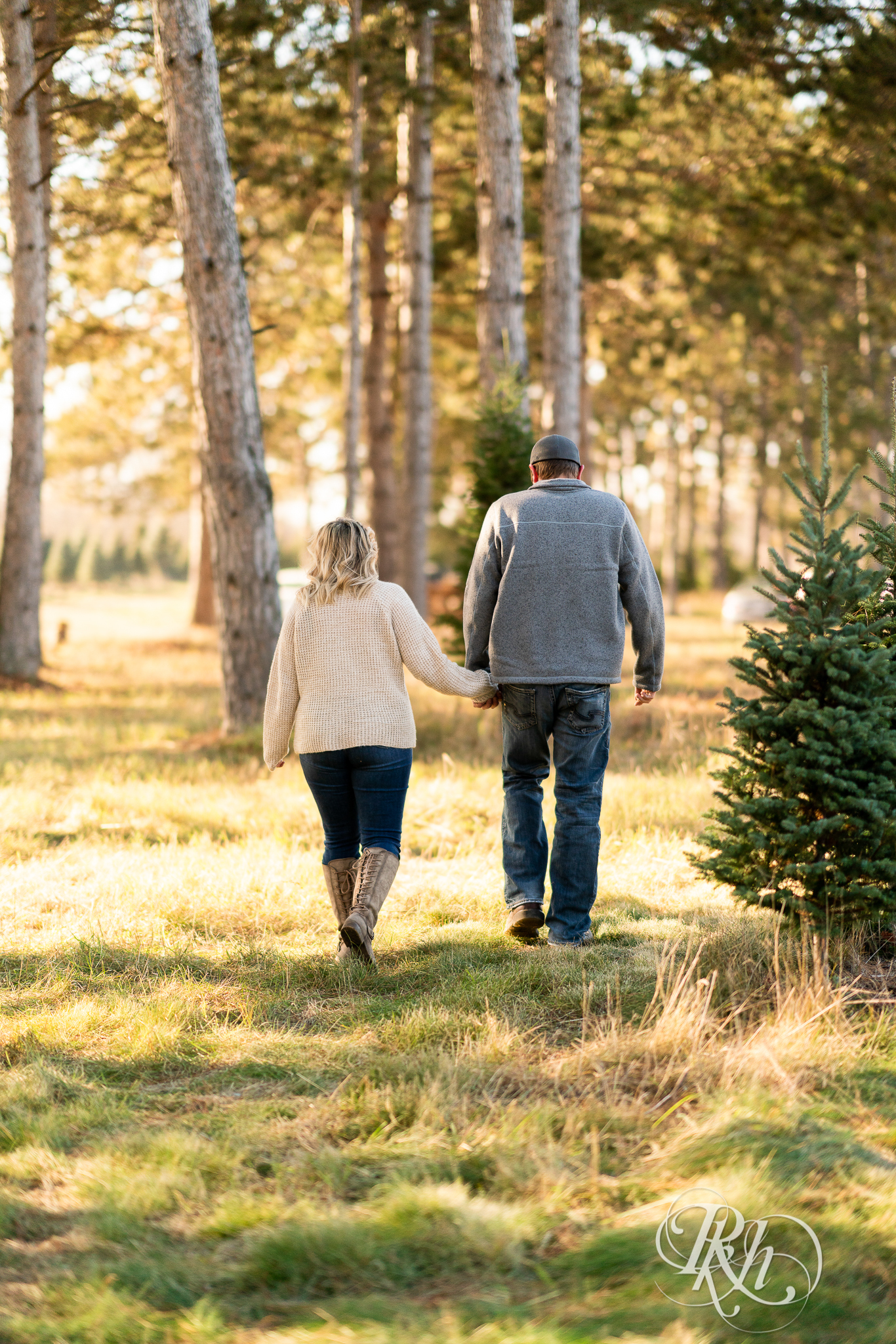 Man and woman walking in sunlight in between trees at Hansen Tree Farm in Anoka, Minnesota.
