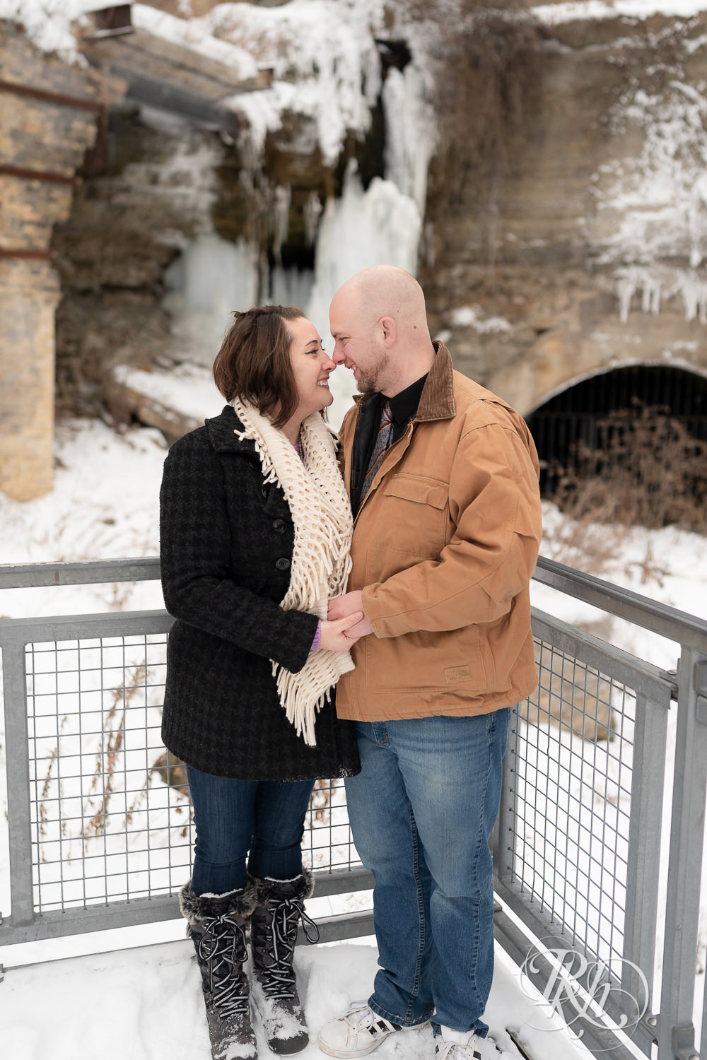 Man and woman standing in front of frozen waterfall in snow at Mill City Ruins in Minneapolis, Minnesota.