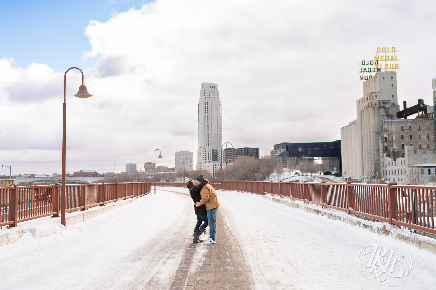 Man and woman kissing in the snow on the Stone Arch Bridge in Minneapolis, Minnesota.