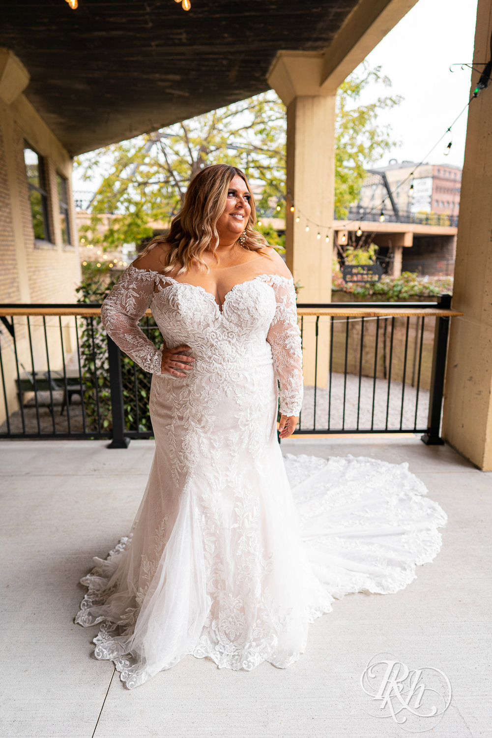 Plus size bride smiling in wedding dresses in Minneapolis, Minnesota with hand on hip.