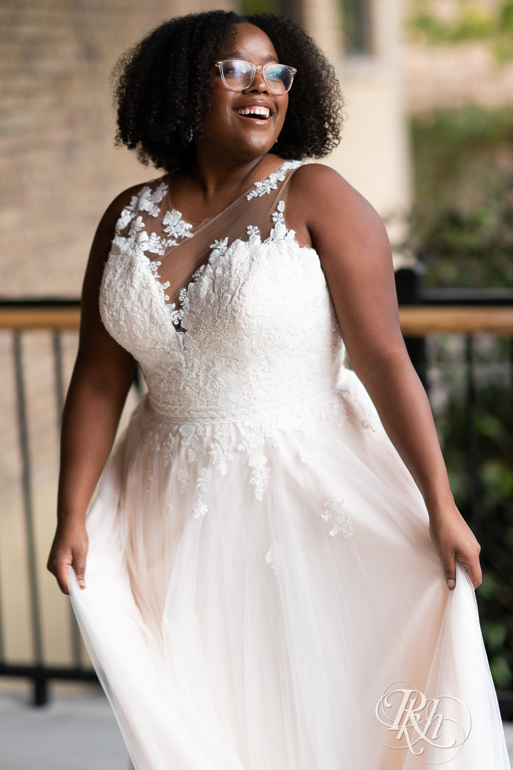 Black plus size bride in glasses smiling in wedding dresses in Minneapolis, Minnesota.