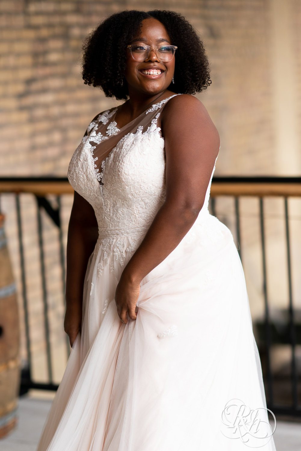 Black plus size bride in glasses smiling in wedding dresses in Minneapolis, Minnesota.