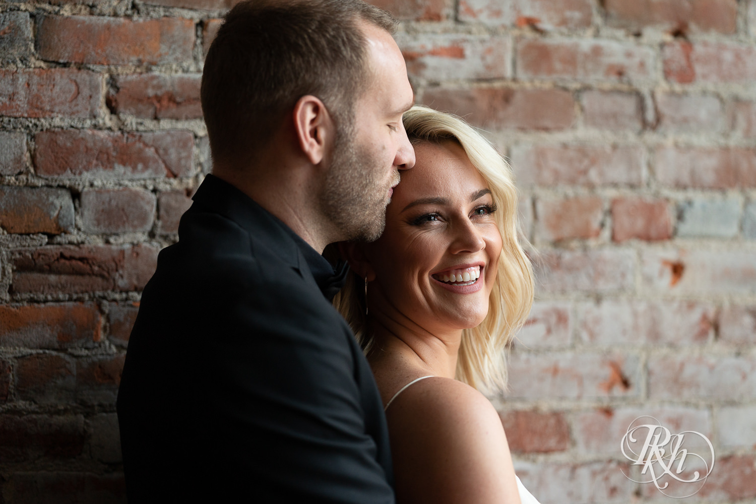 Bride and groom kissing next to brick wall at 3 Ten Event Venue in Faribault, Minnesota.