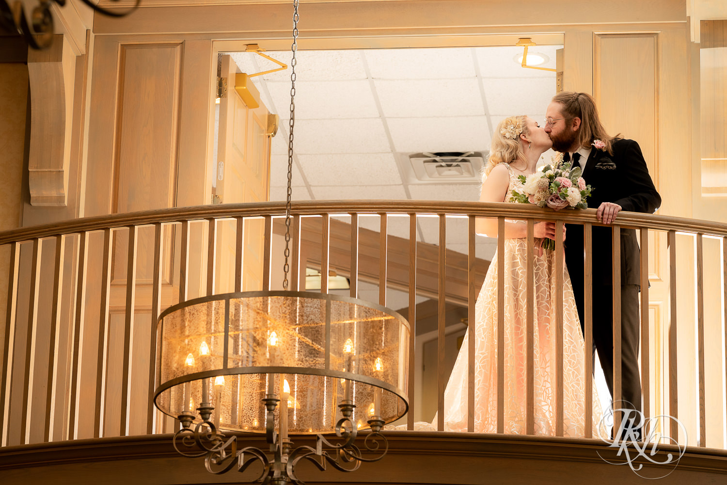 Bride and groom kiss on balcony at Rush Creek Golf Club in Maple Grove, Minnesota.
